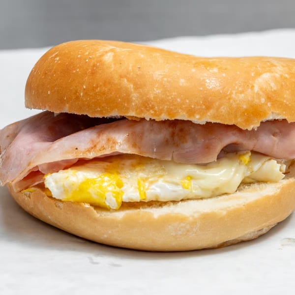 A close-up of a breakfast sandwich with ham, egg, and cheese on a bagel.