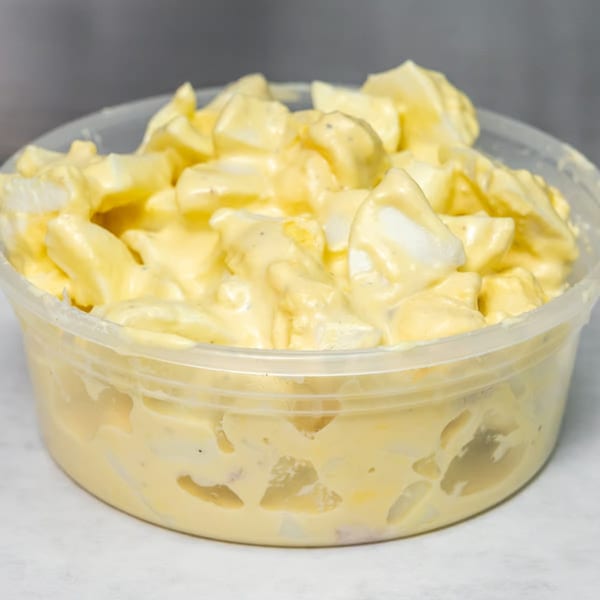 Creamy egg salad with diced eggs in a clear plastic container.